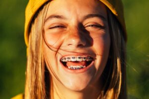 Portrait of beautiful young blonde girl in a yellow cap and a bracket on her teeth.