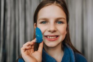 Close-up photo, portrait of beautiful happy smiling girl child teenager face with blue silicone denture, mouth guard for alignment, treatment of uneven teeth in dentistry