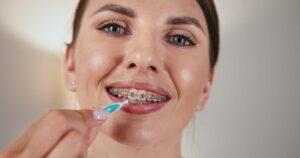 Close-up of young Caucasian woman using dental irrigator to clean braces