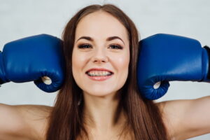 Beautiful boxer girl smiling with braces in blue gloves