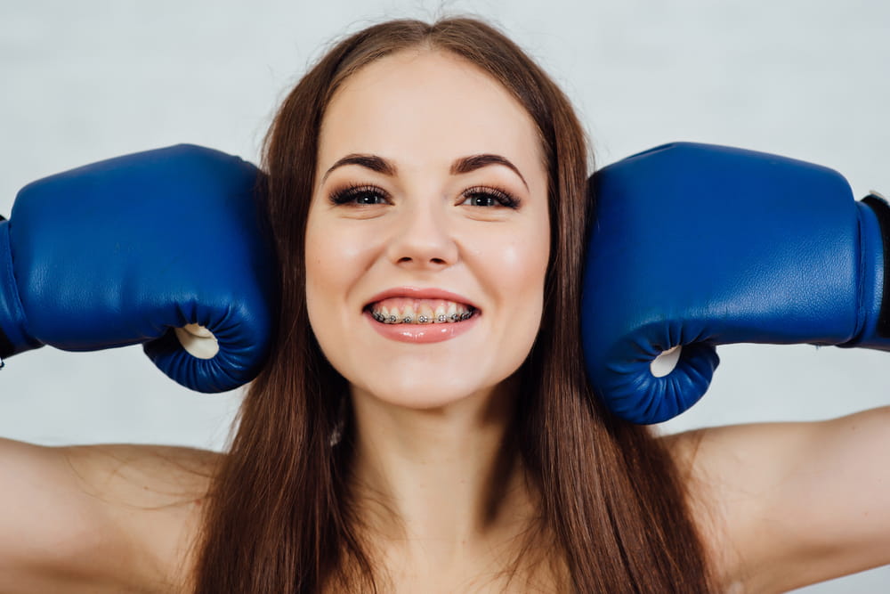 Beautiful boxer girl smiling with braces in blue gloves