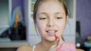 Oral hygiene for braces. Girl teenager indoors cleans braces and teeth with a special brush