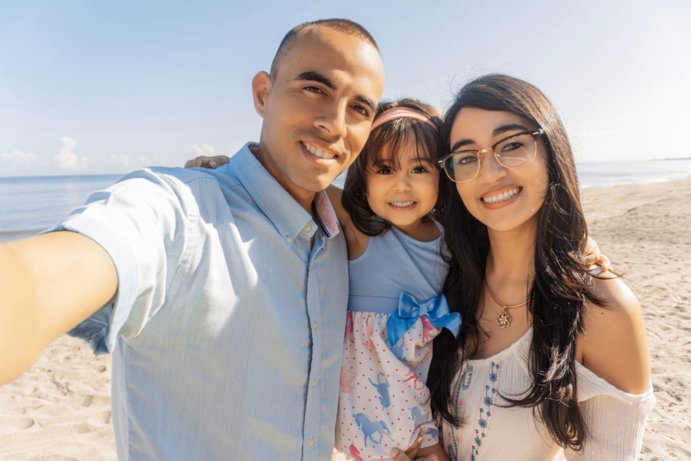 Happy family spending good time at the beach together taking selfie.