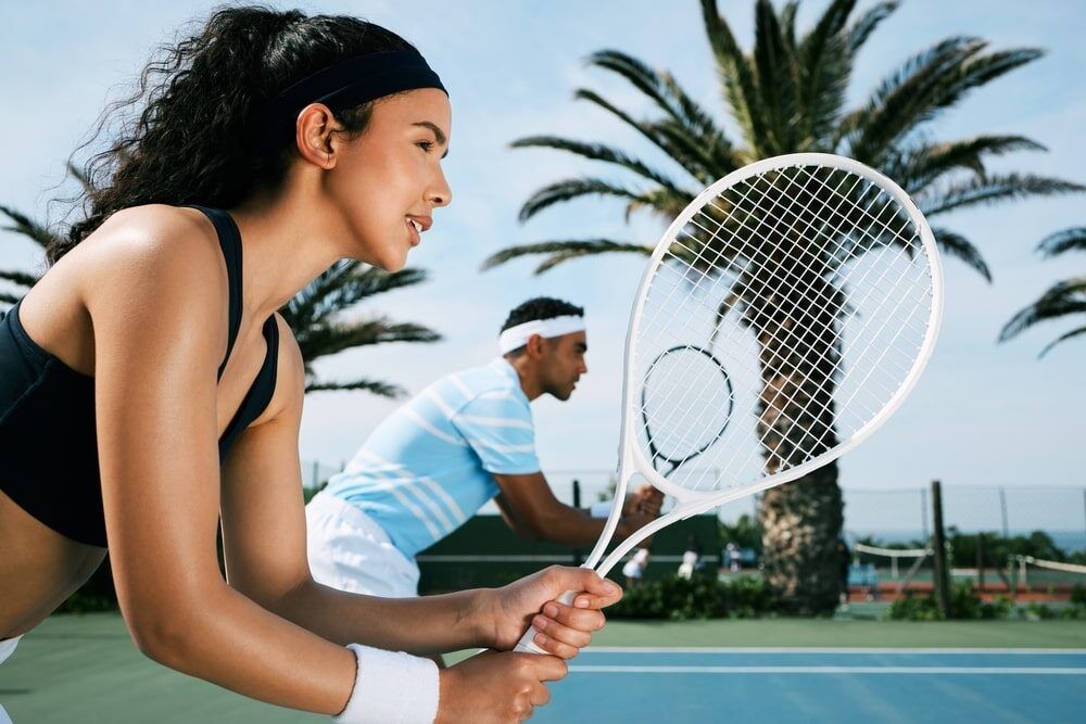 an attractive young woman standing and playing tennis with her teammate.