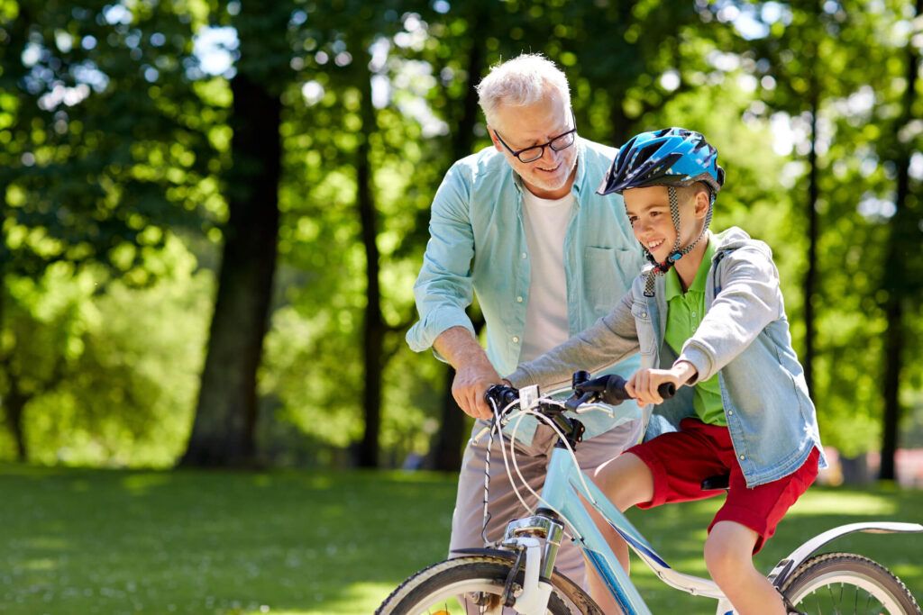 happy grandfather teaching boy how to ride bicycle