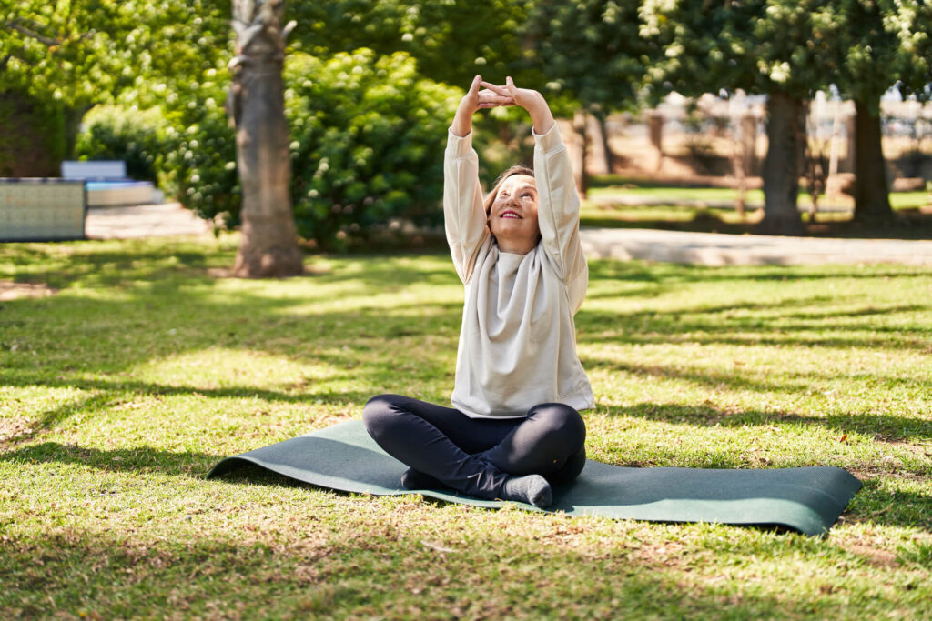 Middle age woman smiling confident stretching at park