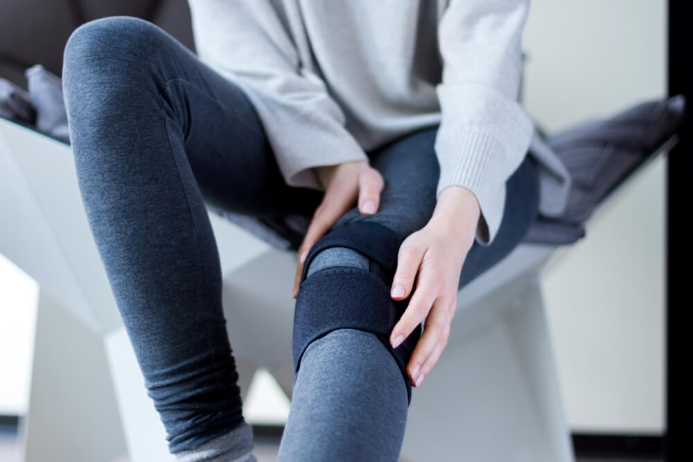 Closeup female leg in grey leggings dressed in knee brace