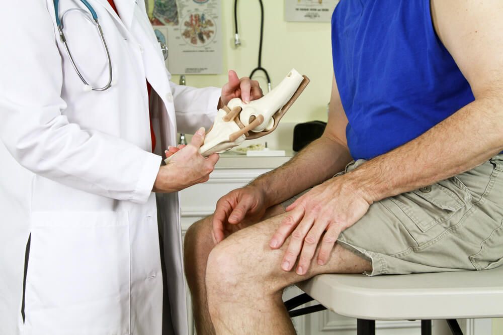 A doctor using a skeletal model of the human knee