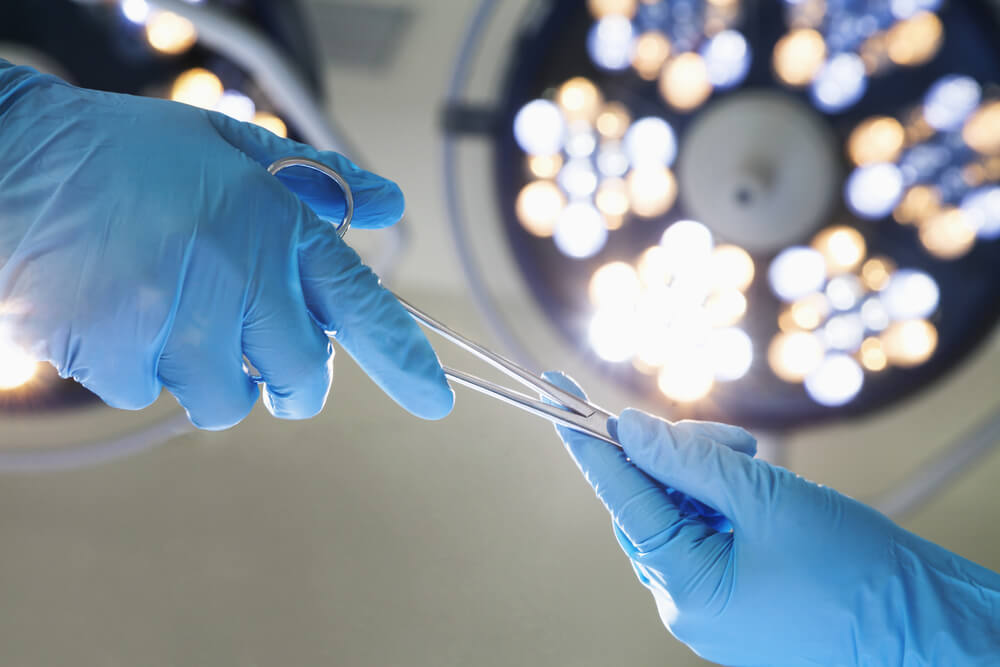 Close-up of gloved hands holding surgical scissors