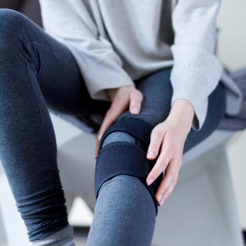 Closeup female leg in grey leggings dressed in knee brace