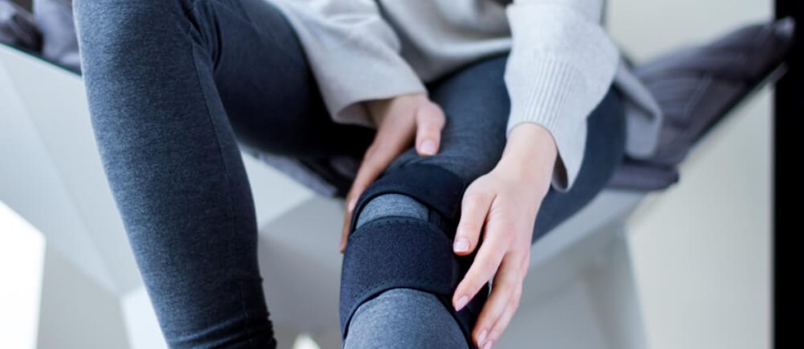 Closeup female leg in grey leggings dressed in knee brace