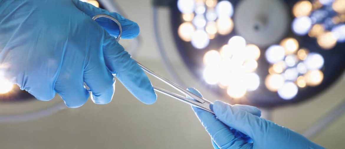 Close-up of gloved hands holding surgical scissors