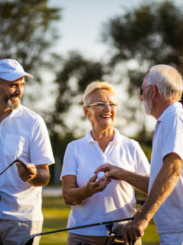 Senior friends on golf court talking.