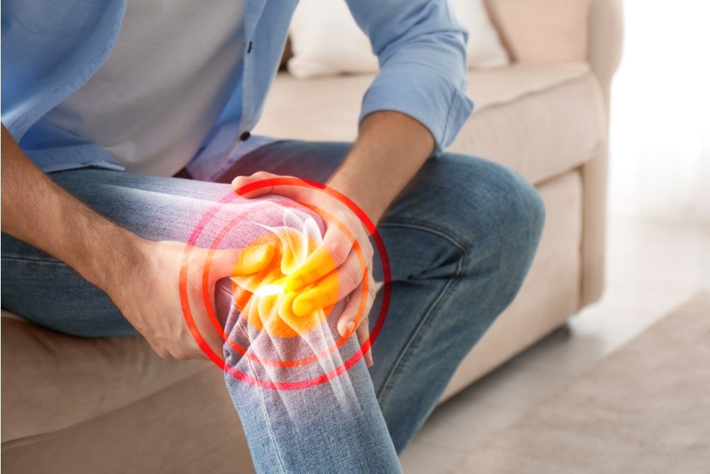 Man suffering from knee pain at home