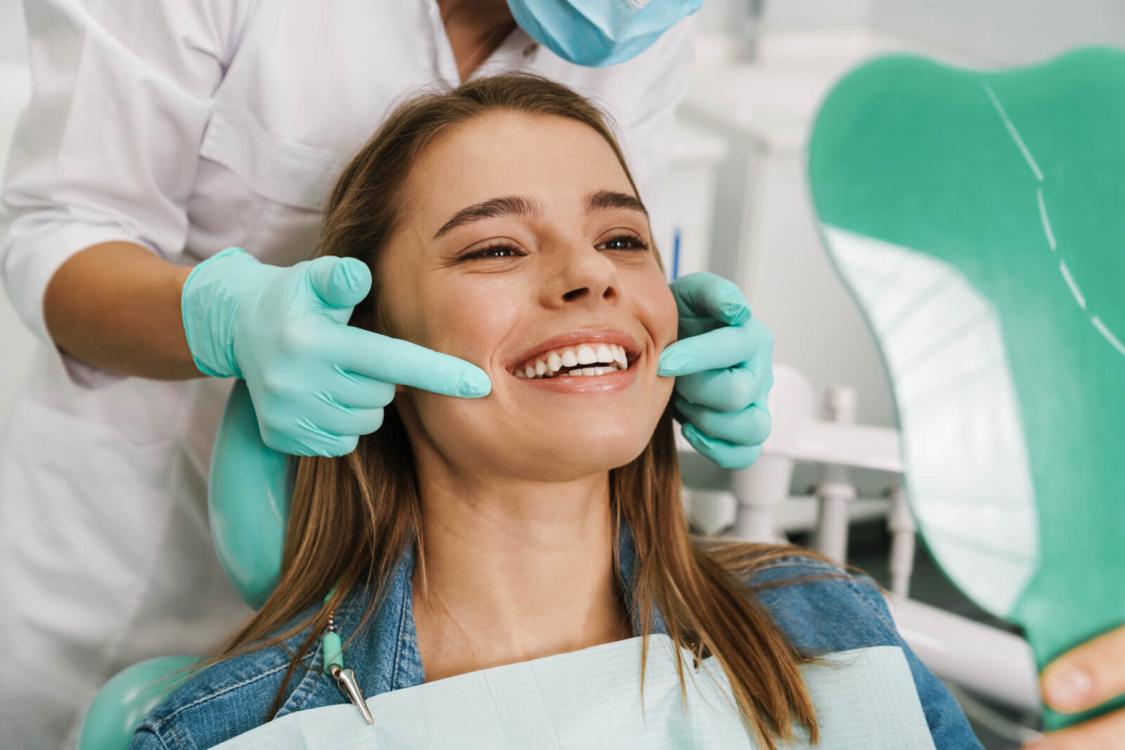 European young woman smiling while looking at mirror in dental clinic