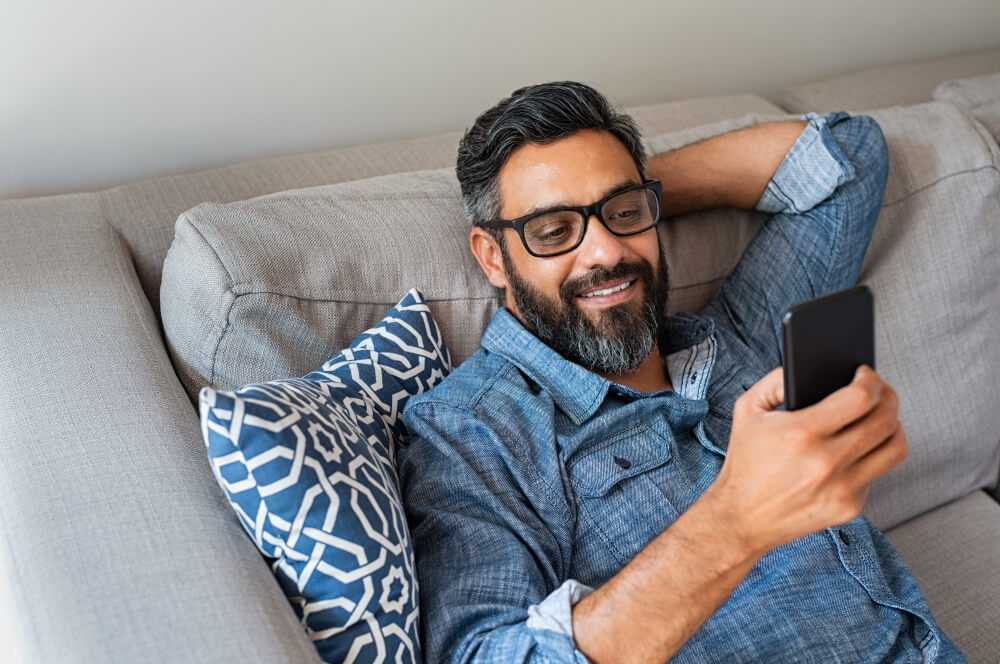 Happy smiling latin man using smartphone