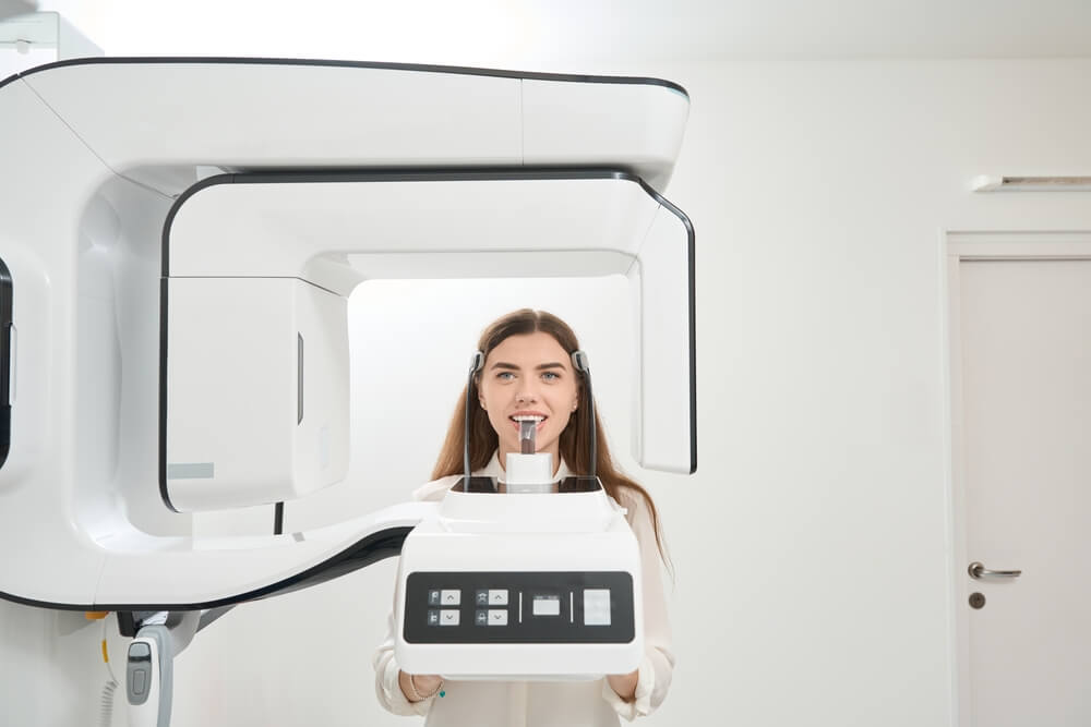 Female patient having her teeth scanned with tomograph