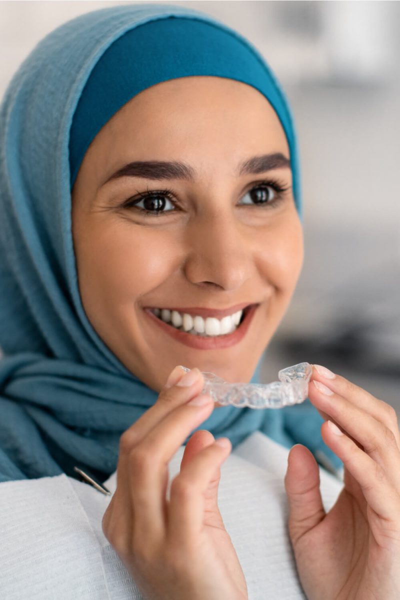 Smiling Muslim Woman In Hijab Holding Invisalign