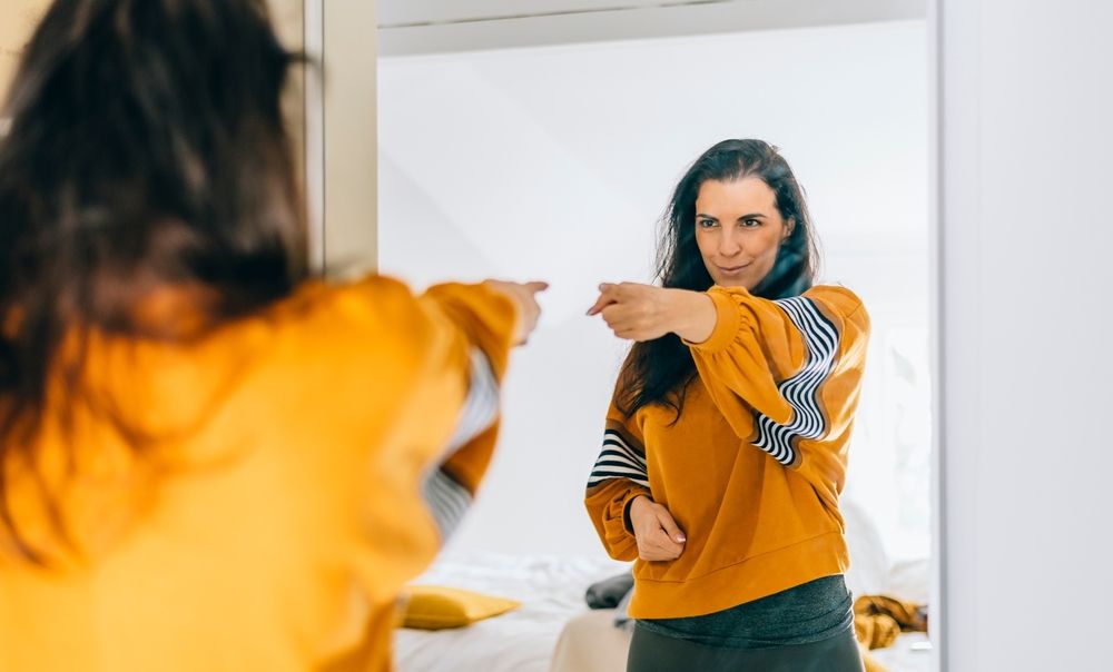 Woman smiling in the mirror, confident, after receiving Injury Management care
