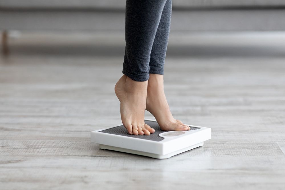 A person on a scale to help with their Weightloss Management 