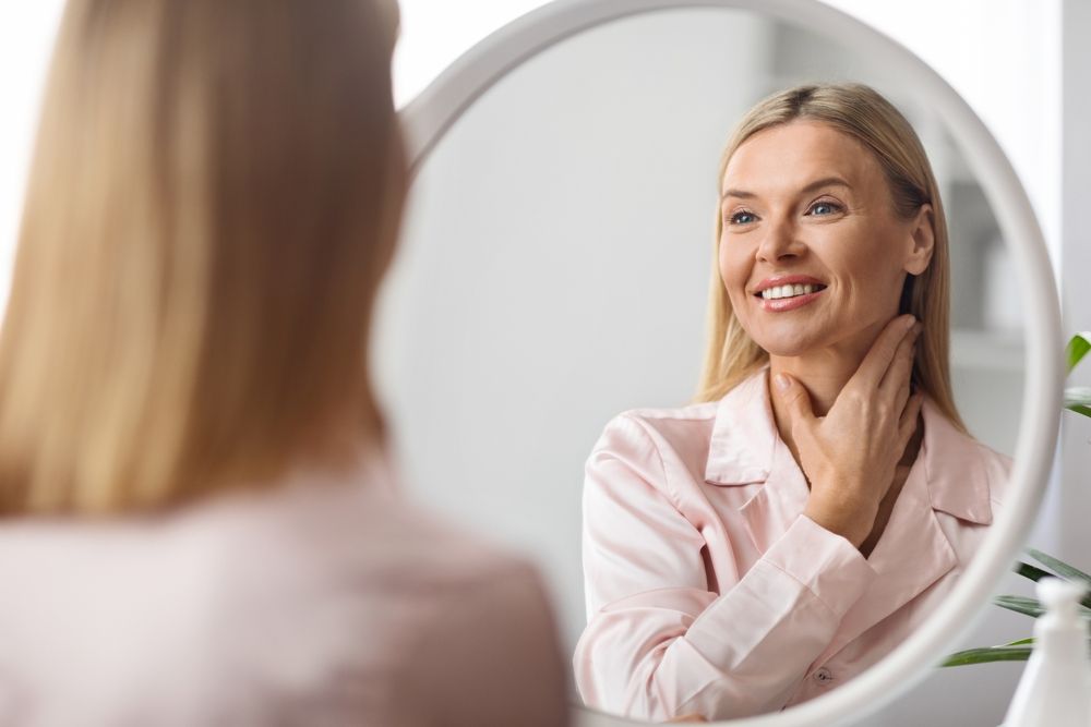 A woman smiling in the mirror after receiving Botox treatment