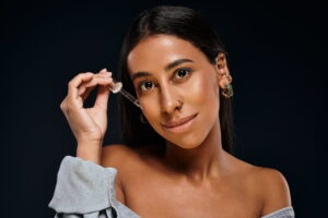 A stunning African American woman showcases her beauty while applying a skincare product.
