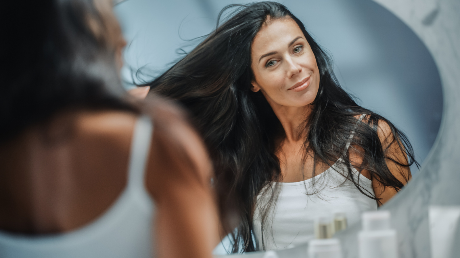 Beautiful Early Middle Aged Woman Looks into Bathroom Mirror