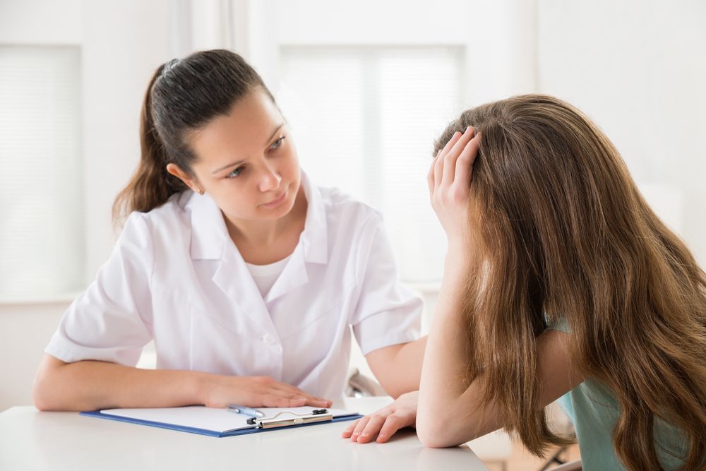 Female Doctor Comforting Depressed Patient Sitting At Table