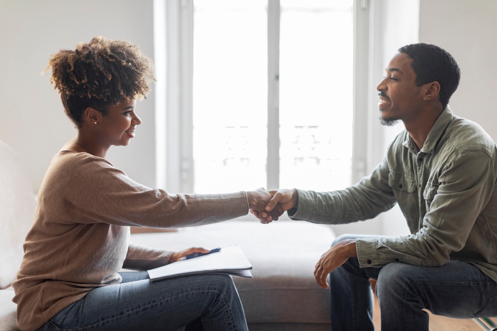 Happy cheerful guy shaking hand with therapist attractive young woman