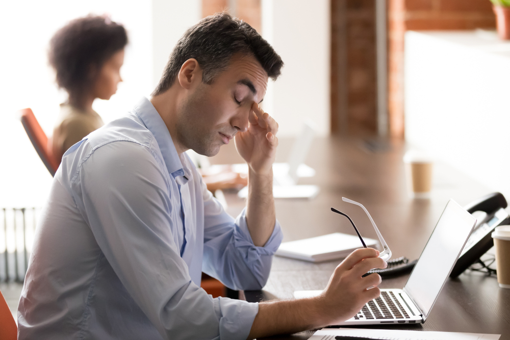 Tired stressed middle aged man holding glasses feel eye strain at workplace