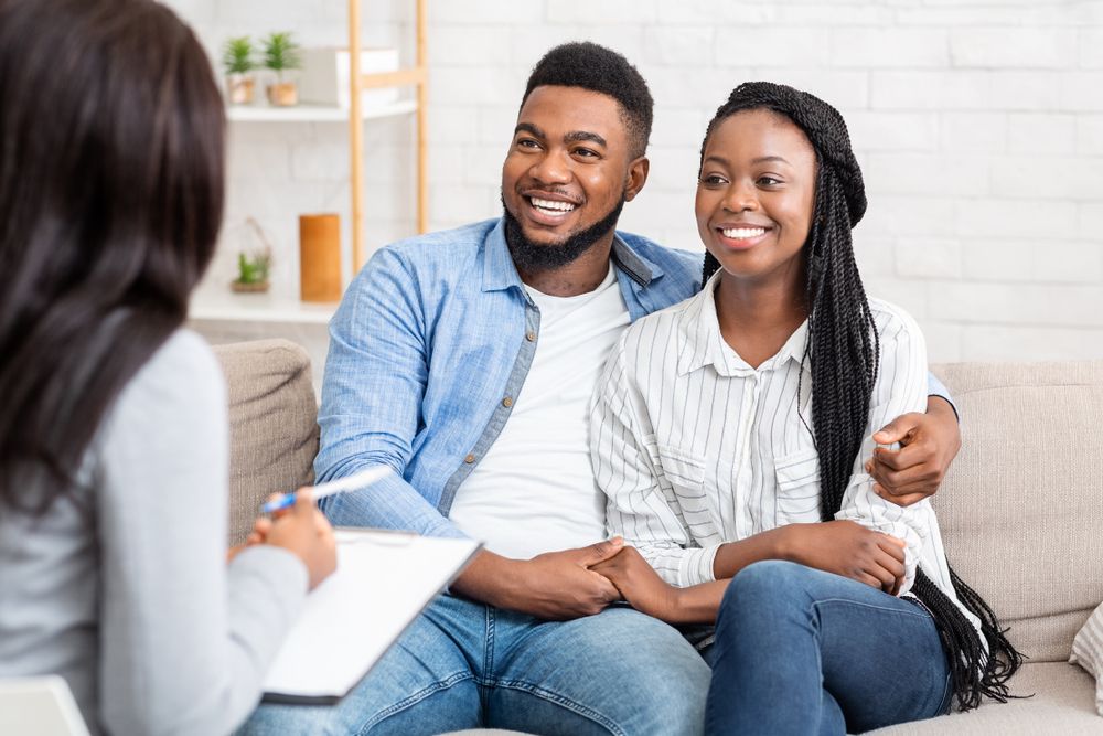 Happy couple sitting in counselor's office after successful marital therapy