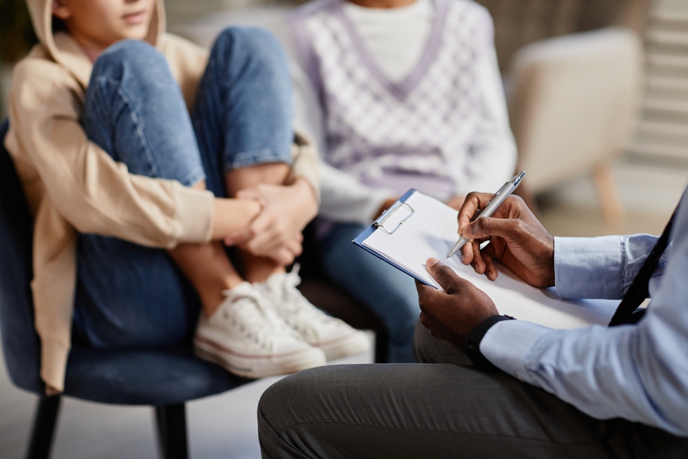 psychologist taking notes on clipboard in therapy session for children