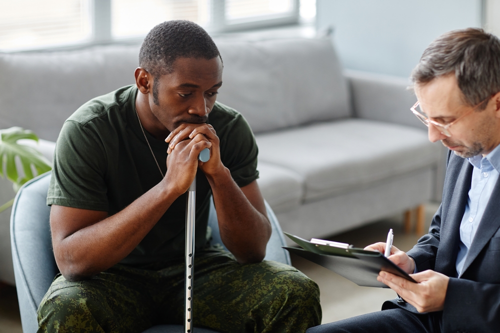 Depressed young adult soldier with walking stick treating PTSD