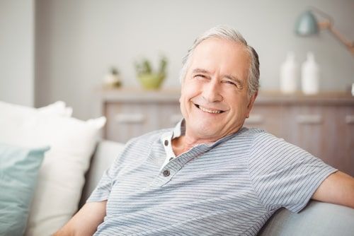 Aged man smiling and sitting on couch
