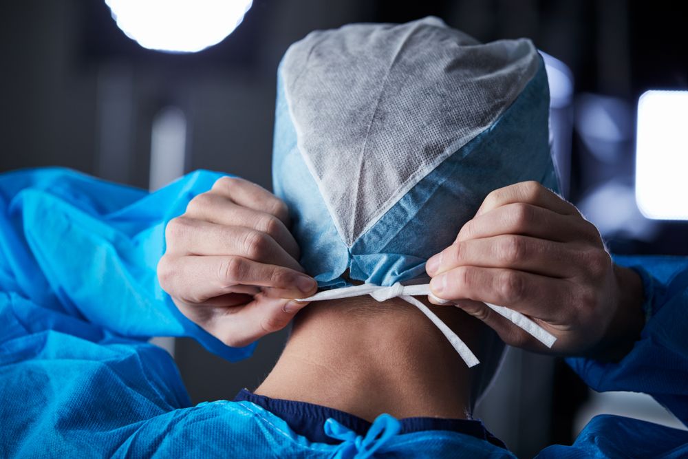 Surgeon,Tying,Surgical,Cap,In,Preparation,,Back,View