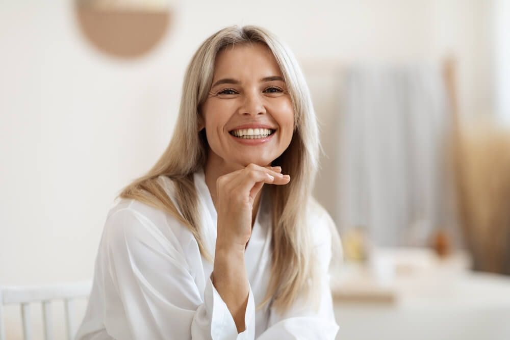 Happy attractive blonde woman in white silky bathrobe