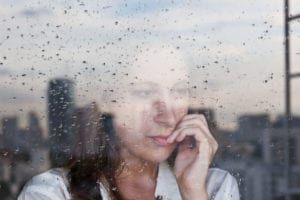 Depressed woman looking out from window