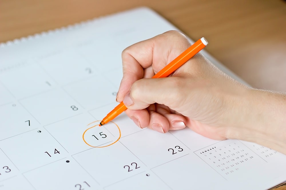 A female hand circling the date of the 15th day in the calendar