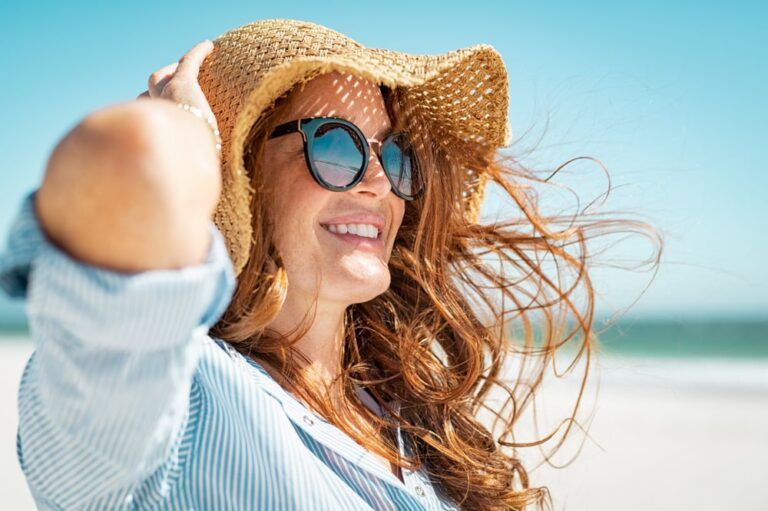 Side view of beautiful mature woman wearing sunglasses at beach