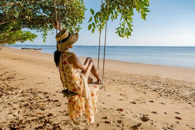 Happy traveler woman in hammock relaxing on the swing