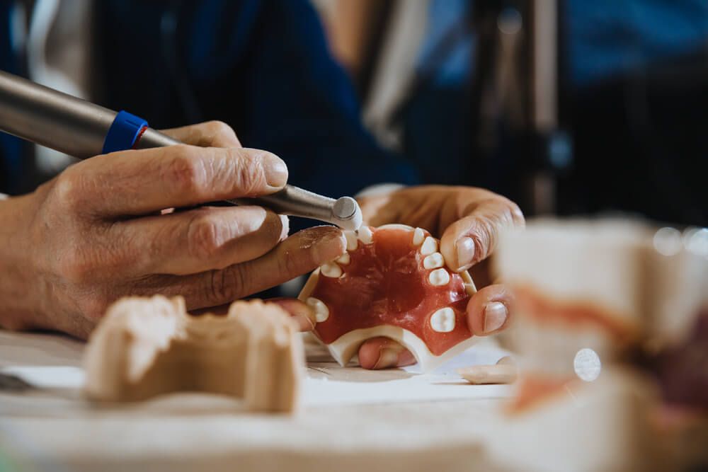 A dental technician processes a cast from the jaw of the patient.