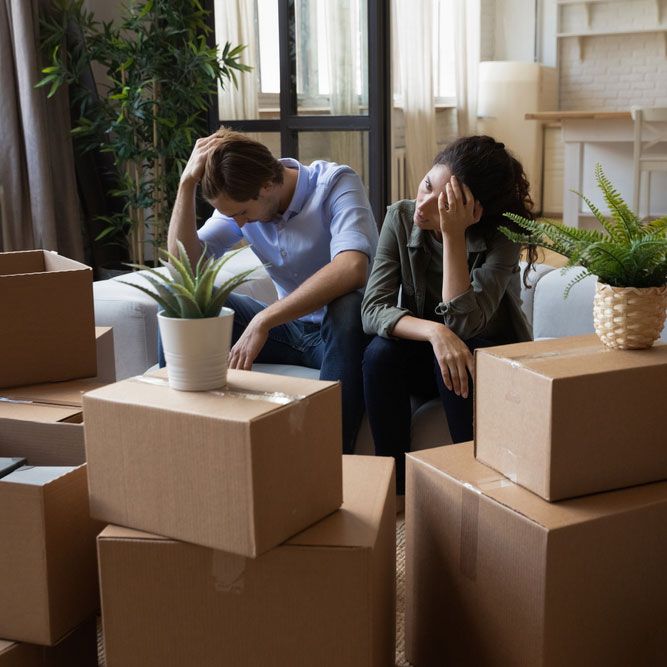 Unhappy frustrated couple sitting on couch with cardboard boxes