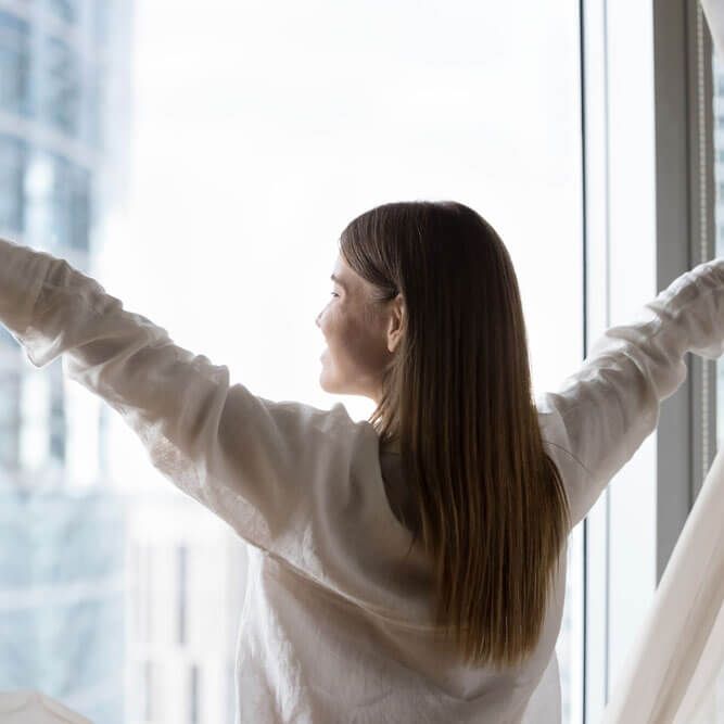 Luxury apartment owner or female traveler opens curtains, welcoming new day