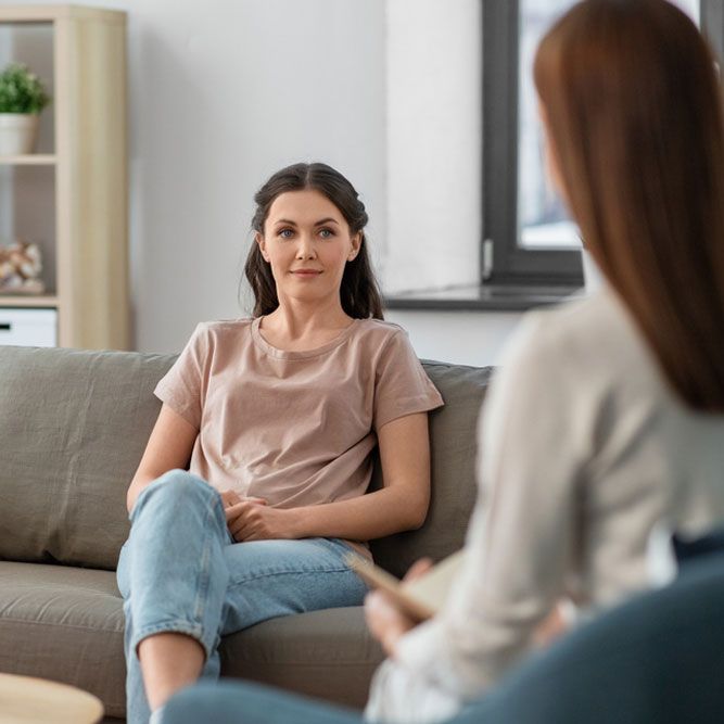 psychology, mental health and people concept - young woman patient and woman psychologist at psychotherapy session