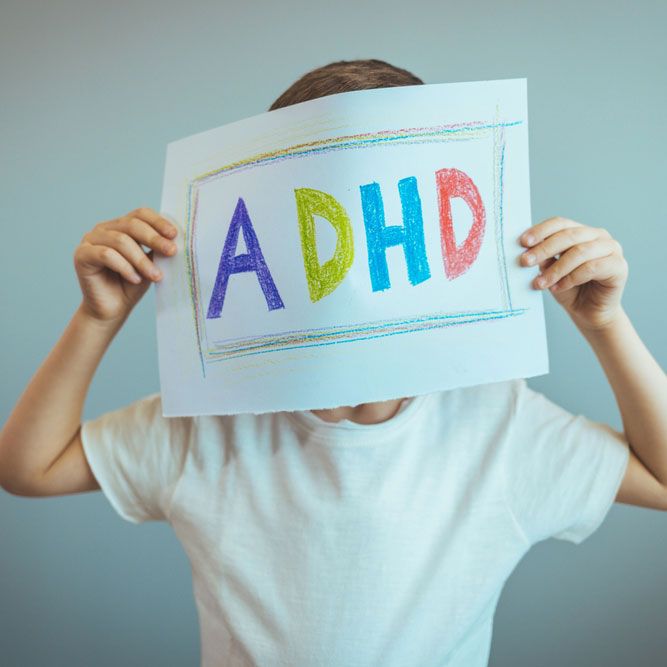 Young boy holds ADHD text written on sheet of paper.
