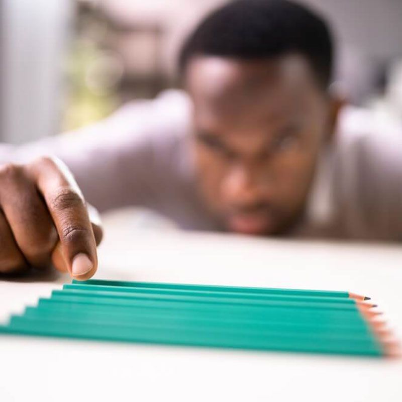 Hand arranging green pencils in a line on a table, discussing worsening OCD symptoms in NYC.