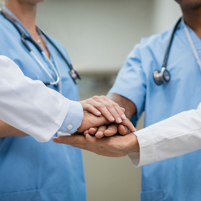 Mature doctors and young nurses stacking hands together