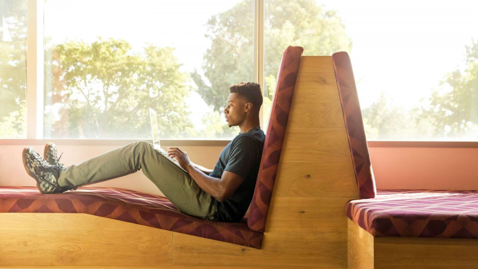 Young man using laptop near window at home