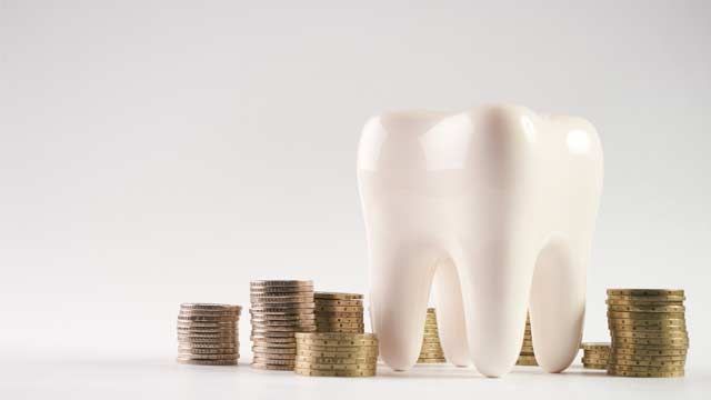 Closeup of a white healthy human tooth model and stacked coins