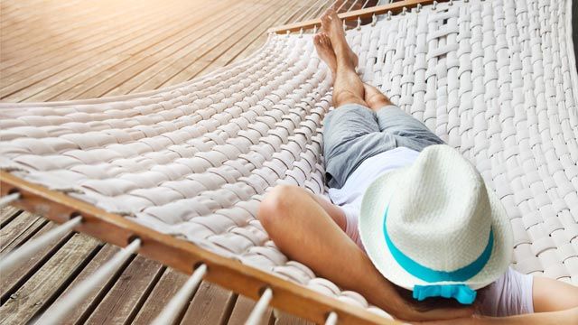 Lazy time. Man in hat in a hammock on a summer day